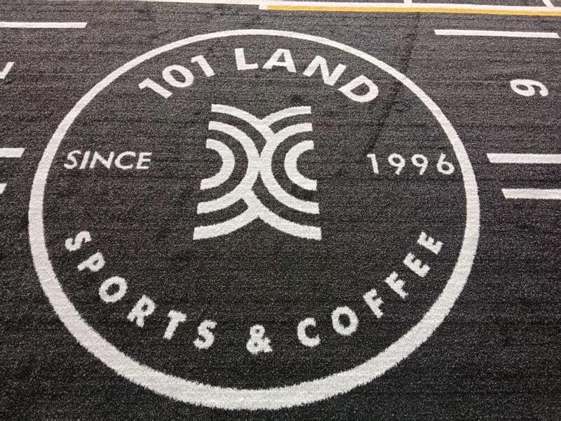 Worker applying adhesive to subfloor for gym track installation